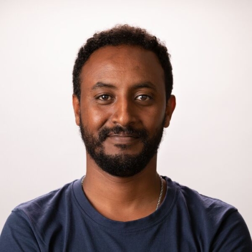Abel Tilahun with a beard and short dark hair, smiling at the camera