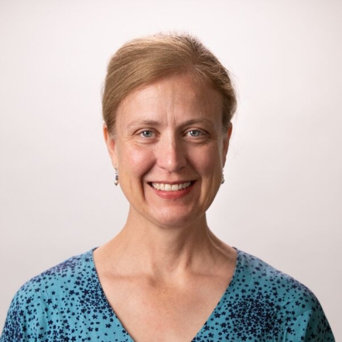 Rose Benson wearing a blue spotted shirt smiling at the camera