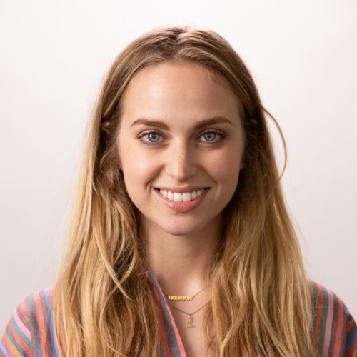 Susannah Eig wearing a striped shirt, with long blonde hair, smiling at the camera.