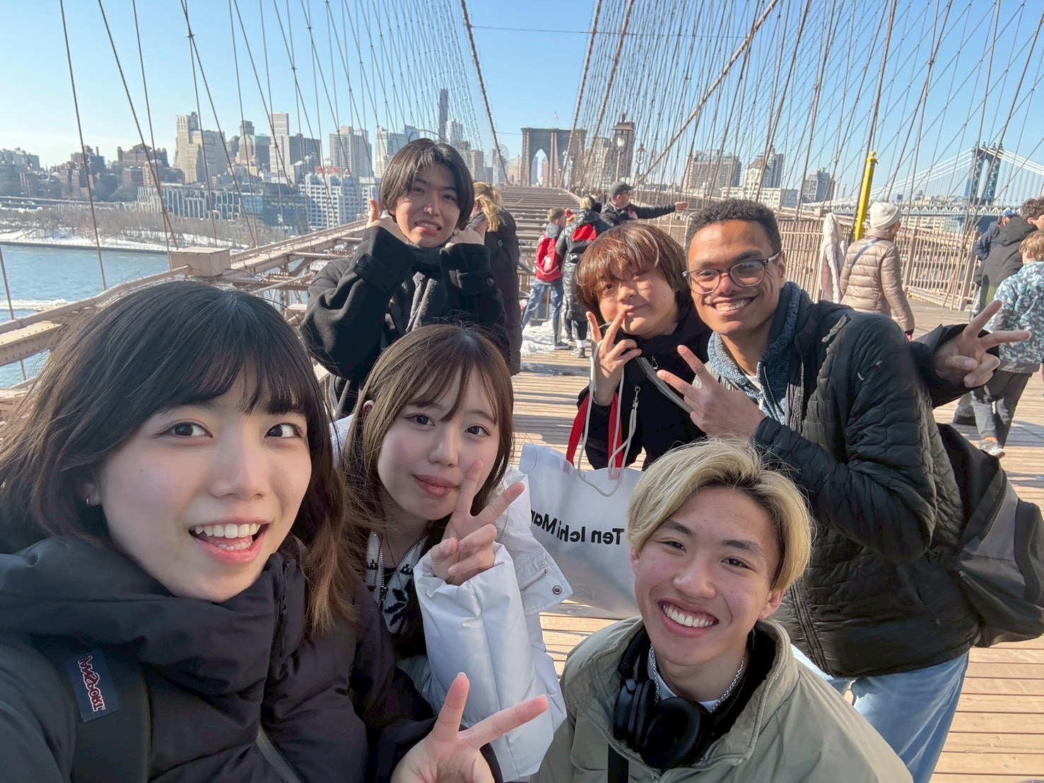 JCC members and exchange students smiling on the Brooklyn Bridge walkway.
