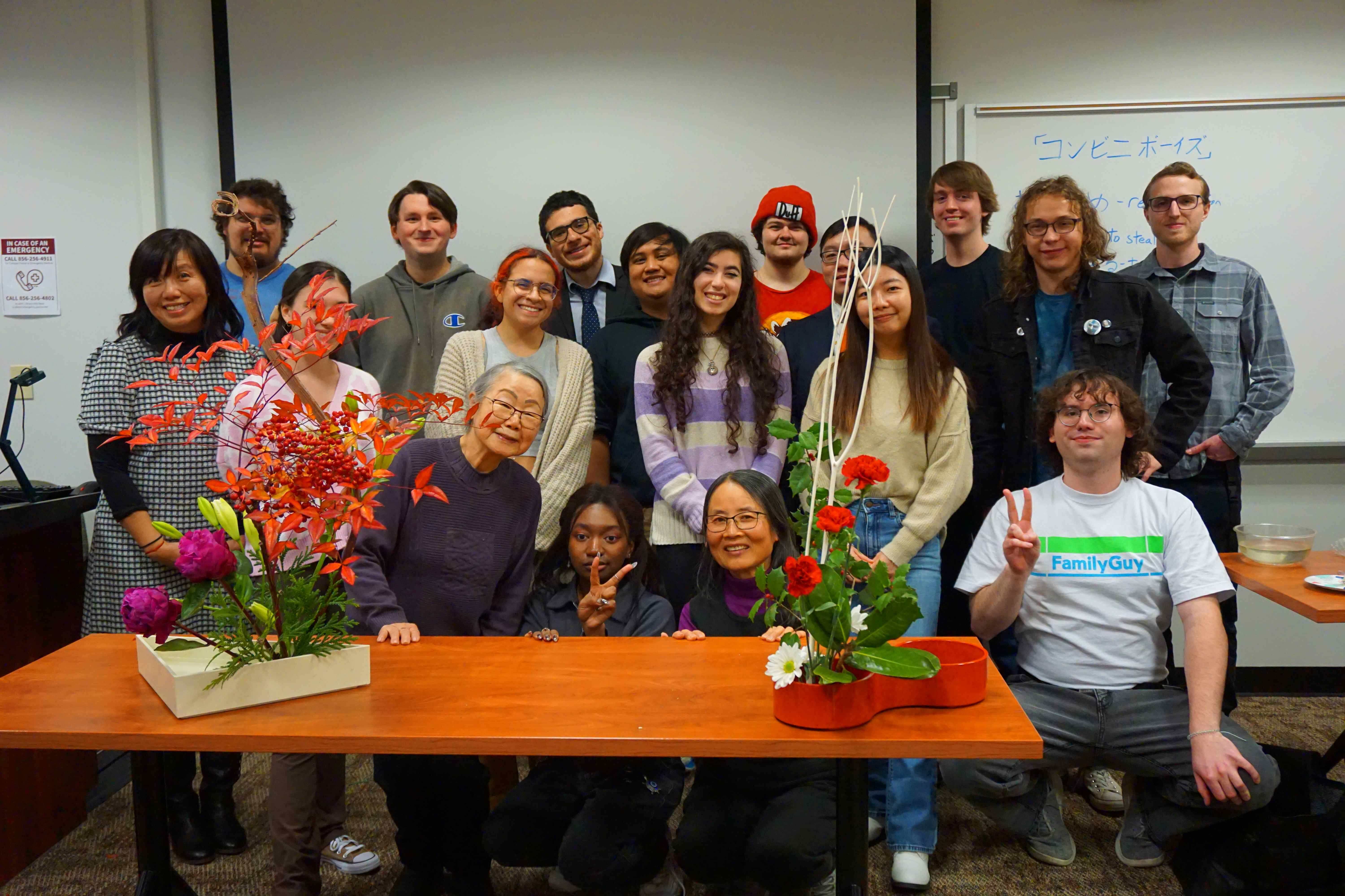 Group of students with Professor Dusk and Mrs. Mariko Ono smiling behind an Ikebana demonstration.