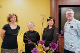 Group of professors smiling behind Ikebana demonstration.