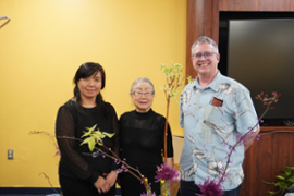 Group of professors smiling behind Ikebana demonstration.