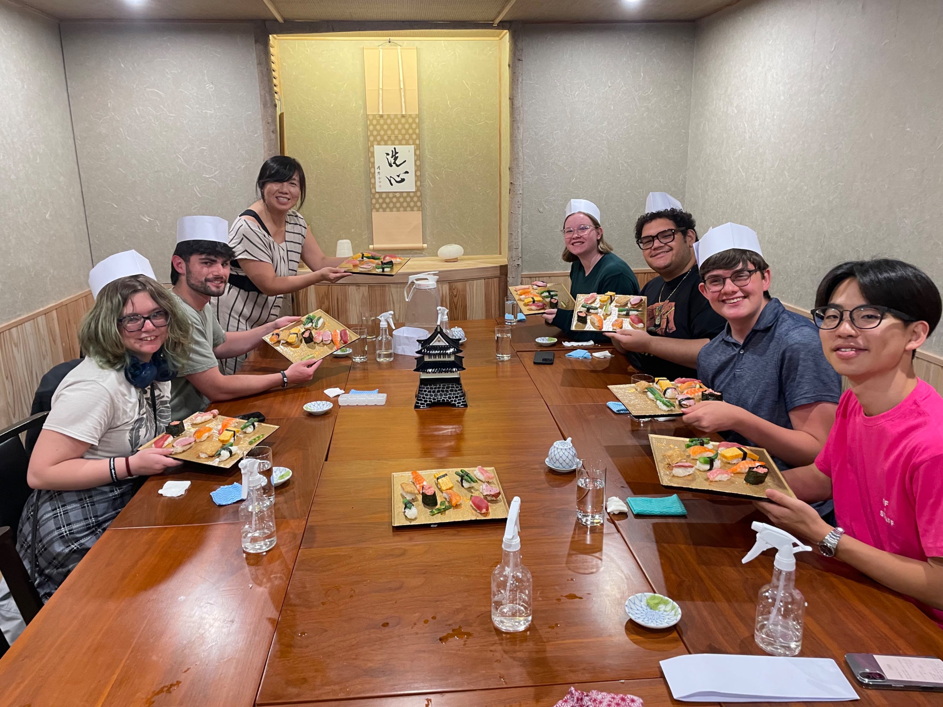 Study abroad group practicing making sushi.