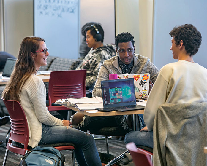 students sitting around a table with their laptops