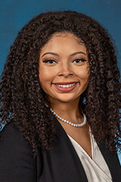 Zania Winfrey smiles into the camera for a headshot while wearing a black blazer over a beige shirt