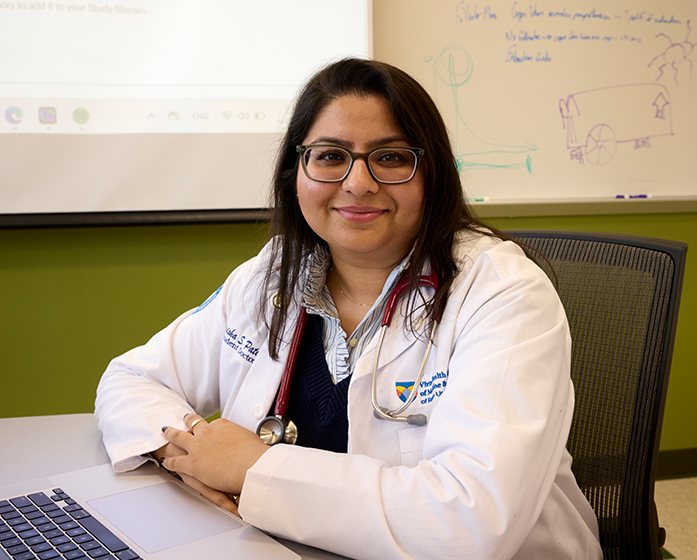 an SOM medical student smiles at the camera while sitting in a classroom
